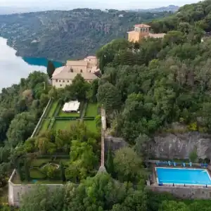 Aerial view of a historic estate with gardens and a swimming pool by the river.